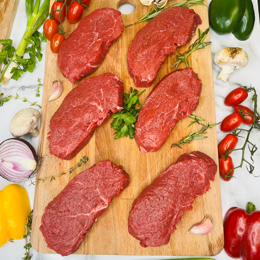 Six rump steaks on a chopping board
