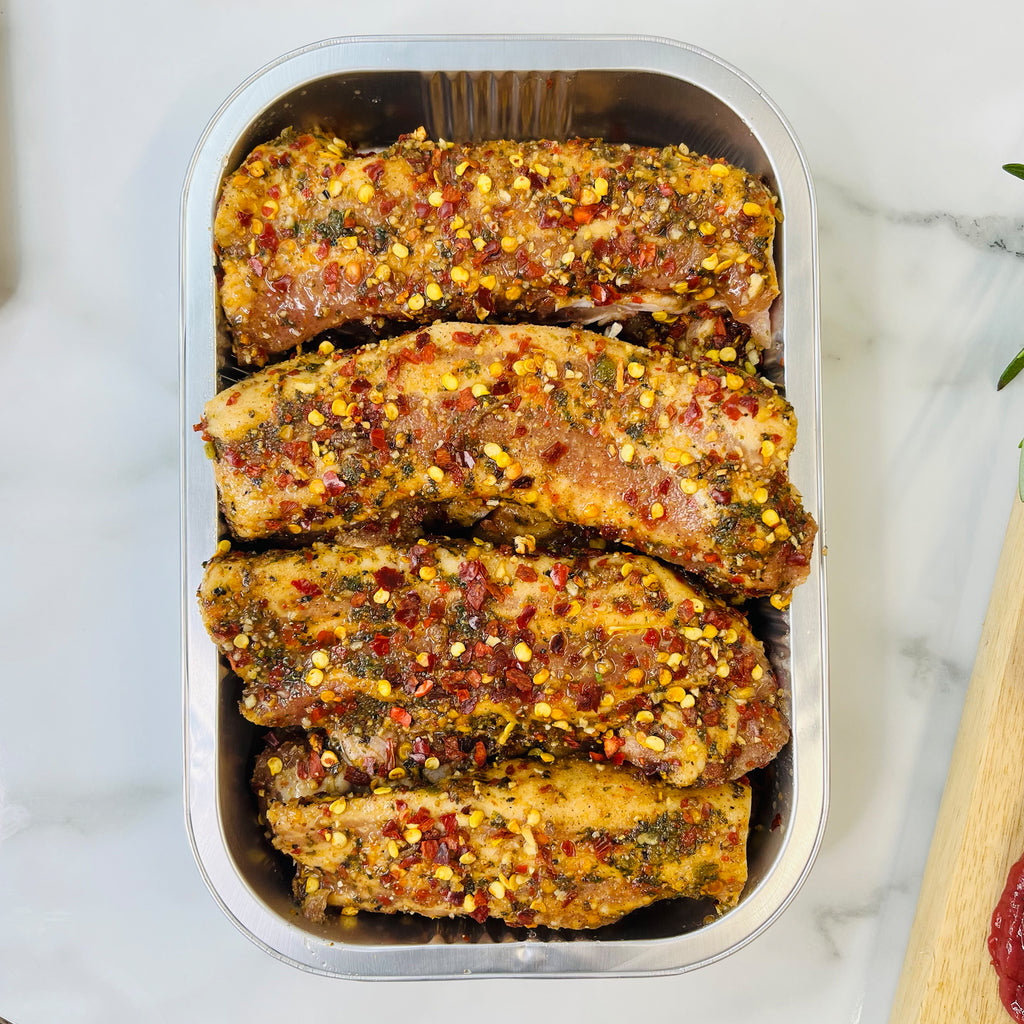 Four boneless pork rib slices with spices in a baking tray