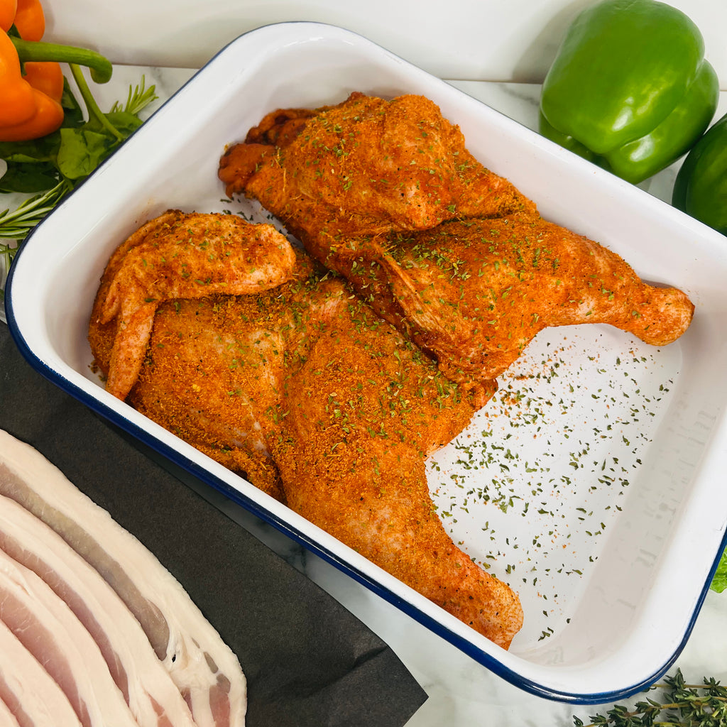 Two Marinated half roasting chickens in a baking tray