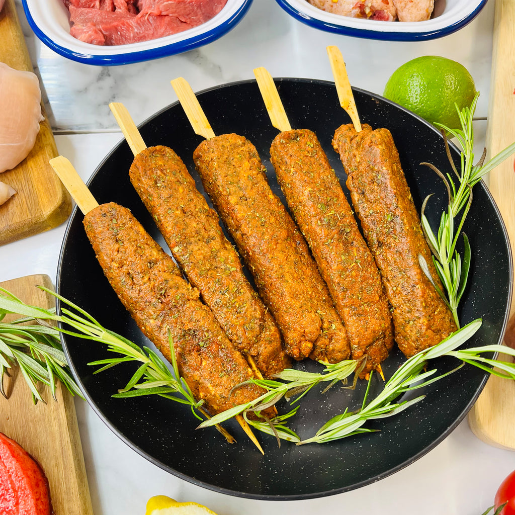 Five Lamb and Mint Kofta Kebabs in a frying pan with rosemary