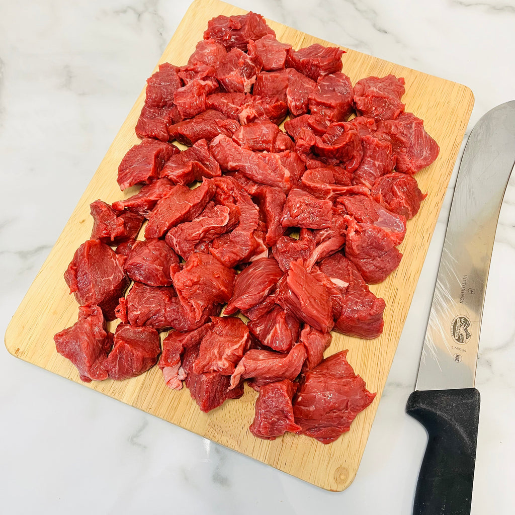 Lean Diced Beef on a chopping board with a knife next to it