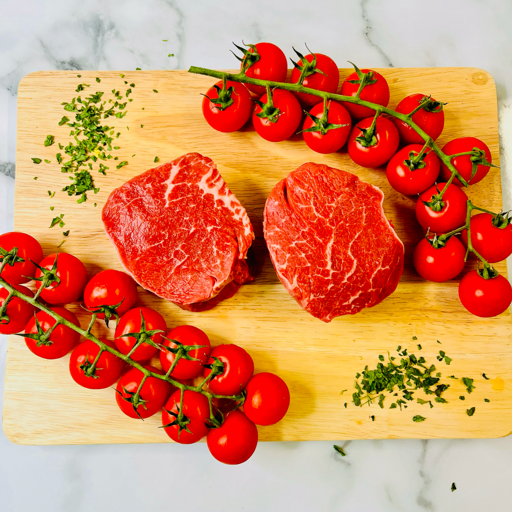 Two Prime British Fillet Steaks, tomatoes and spices on a chopping board