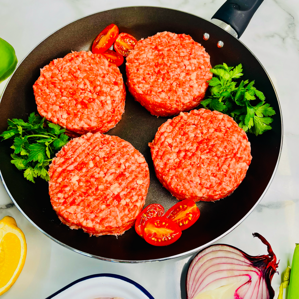 Four British steak burgers on a frying pan