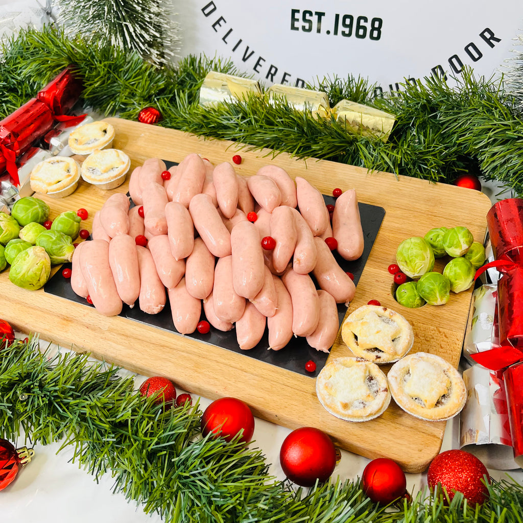 Pork and cranberry chipolatas, mince pies and brussels sprouts on a chopping board