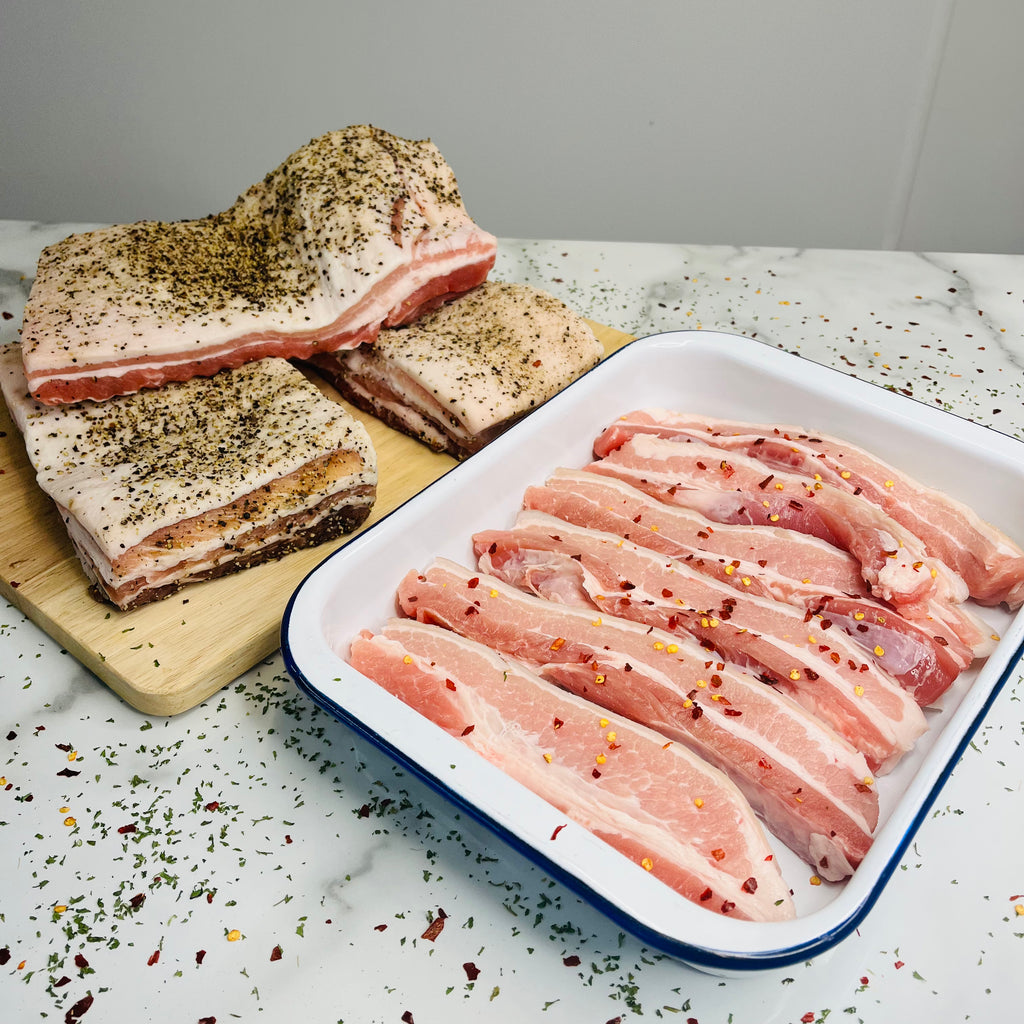 Whole Pork Belly on a chopping board and sliced pork belly in a baking tray 