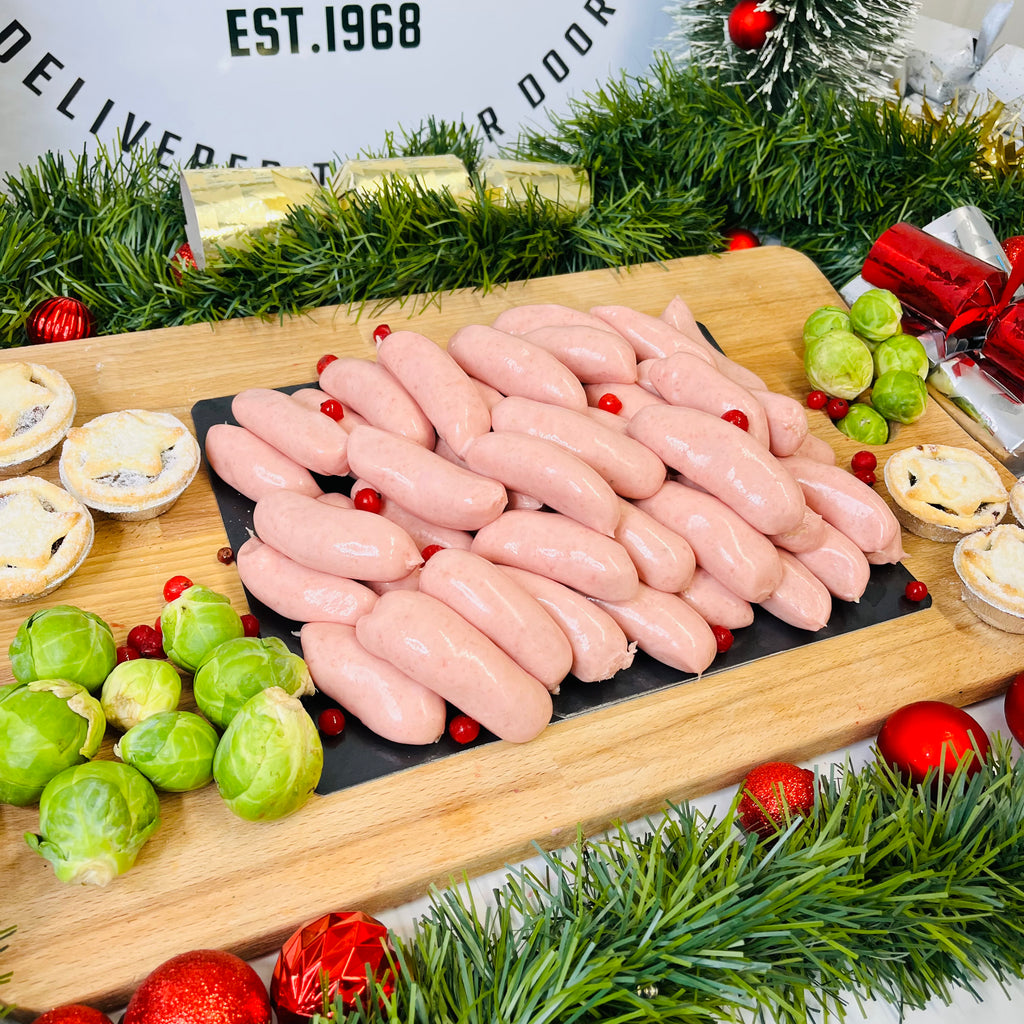 Premium pork chipolatas, mince pies and brussels sprouts on a chopping board